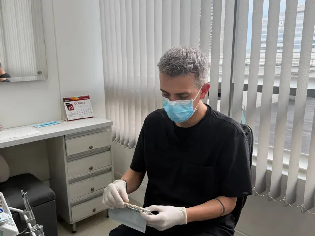 El Dr. Julián Lopera revisa una guía de color dental en su consultorio de StarNova